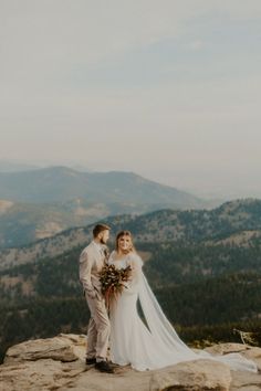 a bride and groom standing on top of a mountain