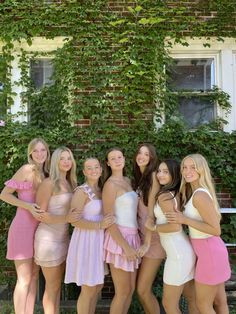 a group of young women standing next to each other in front of a brick building