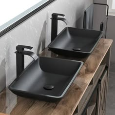 two black bathroom sinks sitting on top of a wooden counter