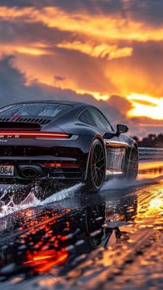 a black sports car driving through water at sunset