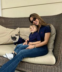 a woman sitting on top of a couch next to a little boy and a dog