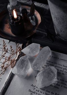 some ice cubes are sitting on top of an open book and next to a candle