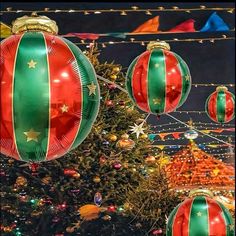 christmas decorations are hanging from the ceiling in front of a large tree with lights on it