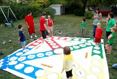 a group of people standing around a giant board game on the ground in a yard