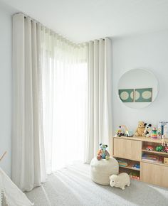 a child's room with white curtains and toys