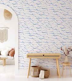 a white room with blue waves on the wall and a wooden table next to it