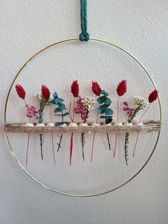 a circle hanging on the wall with flowers in it's center and stones underneath