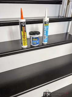 three different types of paint sitting on top of a black and white set of stairs