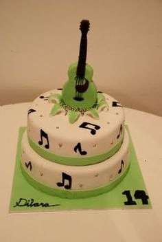 a three tiered cake decorated with musical notes and a guitar on the top layer