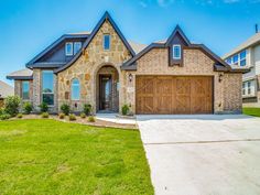 a large house with two garages in the front yard and grass on the side