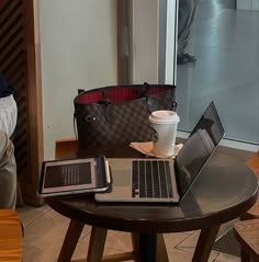 two laptops and a tablet on a table in front of a person with a purse