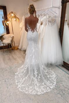 a woman standing in front of a mirror looking at her wedding gowns on display