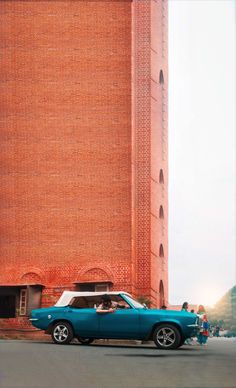 a blue car parked in front of a tall building