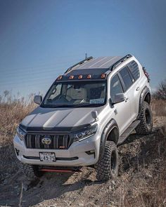 a white suv driving on top of a dirt hill