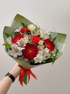 someone holding a bouquet of red and white flowers