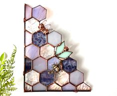 a wall hanging made out of hexagonal tiles with flowers in the corner next to it