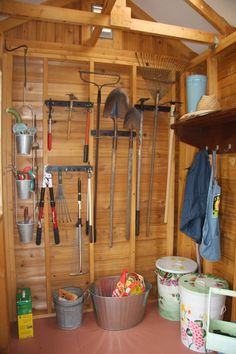 a wooden shed with gardening tools hanging on the wall