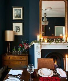 the dining room table is set for dinner with candles and flowers in front of the fireplace