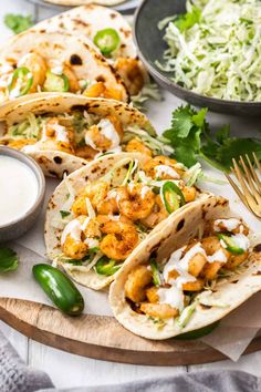 three shrimp tacos on a cutting board with cole slaw