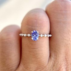 a woman's hand holding a ring with a tanish blue stone in it