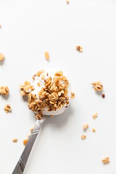 a spoon filled with granola on top of a white surface