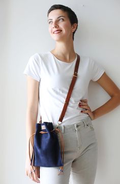 a woman standing with her hands on her hips and holding a blue purse in front of her