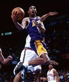 a basketball player jumping up into the air to dunk a ball in front of two other players