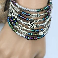 "Fun and festive this seven layer bracelet is sure to make a fresh statement. The layered silver and colored beads give that fun boho vibe which will compliment nearly all outfits, and is perfect for everyday, beach vacations, or special occasions. The one-size-fits-all feature makes this a great gift for any woman. Made with memory wire, a kind of wire that never loses its shape. You simply wrap the bracelet around your wrist. The bracelet coils wrap around the wrist and gives the impression of Bohemian Multi-strand Beaded Bracelets With Silver Beads, Adjustable Silver Bohemian Wrap Bracelet, Multicolor Bohemian Beaded Bracelets With Silver Beads, Silver Bohemian Multi-strand Wrap Bracelet, Silver Beaded Bohemian Wrap Bracelet, Silver Beaded Bracelets Bohemian Style, Silver Multi-strand Bracelets With Spacer Beads, Handmade Silver Multi-strand Wrap Bracelet, Bohemian Multicolor Bracelets With Silver Beads