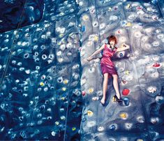 a woman laying on top of a climbing wall