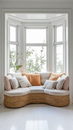 a couch sitting in front of two windows with pillows on it's back end