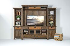 an entertainment center with a large screen tv and wicker baskets on the bottom shelf