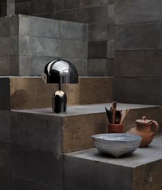 a table lamp sitting on top of cement steps next to a bowl and vases