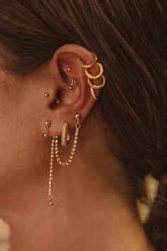 a close up of a person with ear piercings and gold jewelry on their ears