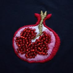 an embroidered pomegranate on a black shirt with red beads and sequins