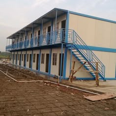 a blue and white building with stairs leading up to the second floor, next to a parking lot