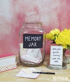 a jar filled with cards and flowers on top of a table next to a card holder