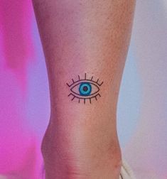 a small tattoo on the ankle of a woman's leg with an evil eye