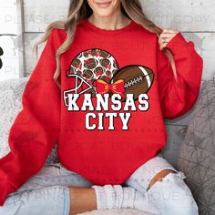 a woman sitting on a couch wearing a red kansas city sweatshirt with football and helmet