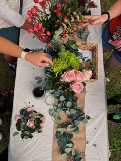 two people are arranging flowers on a table