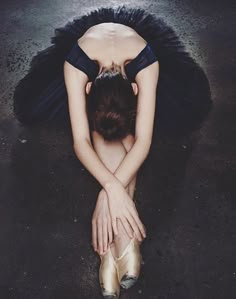 a woman is sitting on the ground with her head in her hands and wearing ballet shoes