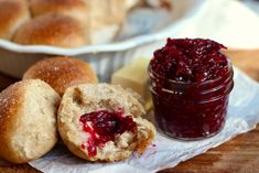 some cranberry jelly is in a jar next to rolls and butter on a napkin