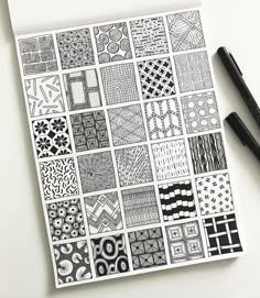 some black and white designs on a piece of paper with two pens next to it