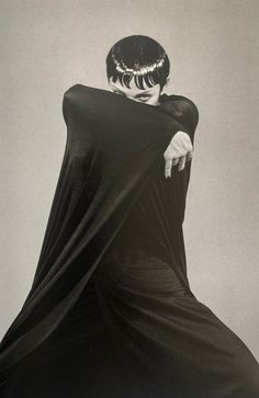 a black and white photo of a man in a cape with his hands on his hips