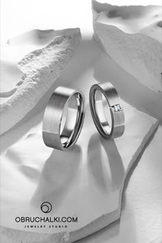 two wedding rings sitting on top of a rock