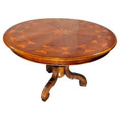 a round wooden table with an intricate design on it's center and four legs