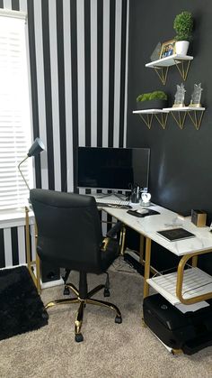 a black and white striped wall in an office with a desk, chair, computer monitor and printer