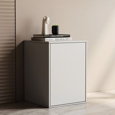 a white cabinet sitting next to a wall with a book on it's top