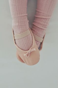 a person wearing pink ballet shoes with their feet in the air and holding on to them