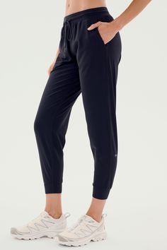 A person is shown wearing SPLITS59's Classic Airweight Jogger in Black and white athletic shoes. The focus is on the side view of the lower body, perfect for a workout. Sporty Jogging Pants With Functional Drawstring, Black Breathable 4-way Stretch Pants, Black Athleisure Bottoms, Sporty Joggers With Functional Drawstring, Black Tapered Leg Sweatpants For Gym, Black Casual Stretch Activewear, Casual Black Stretch Activewear, Black Stretch Casual Activewear, Athleisure Joggers With Functional Drawstring