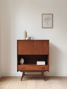 a wooden cabinet with two drawers and a vase sitting on it's top shelf